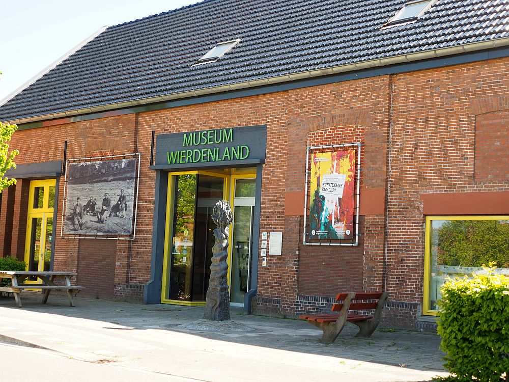 The front of the museum: a plain, one story red-brick building with doors in the center and a few signs advertising special exhibitions. 