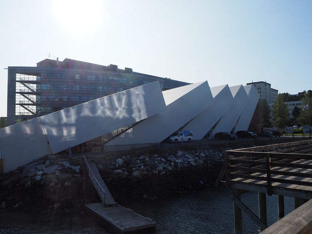 The building looks like white, square dominos have just been knocked over. The one on the left leans the closest to horizontal. 