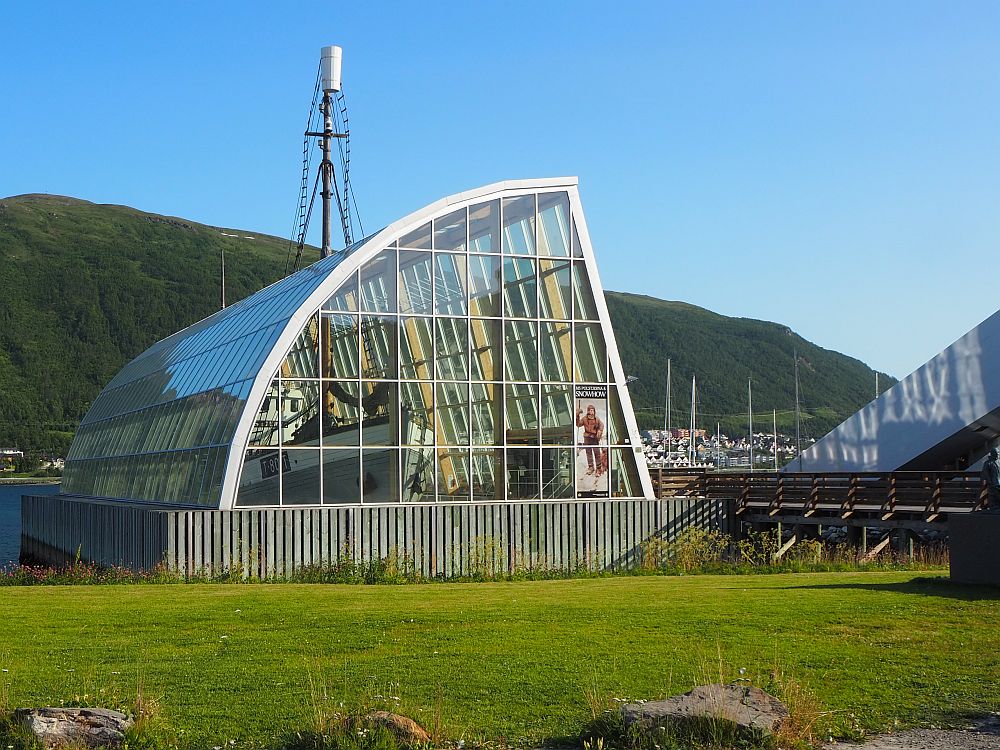 The glass building is basically shaped like a quarter of a cylinder, placed on on the flat sides. the side facing right is also flat and the side facing left is curved. The boat can be seen through the glass. 