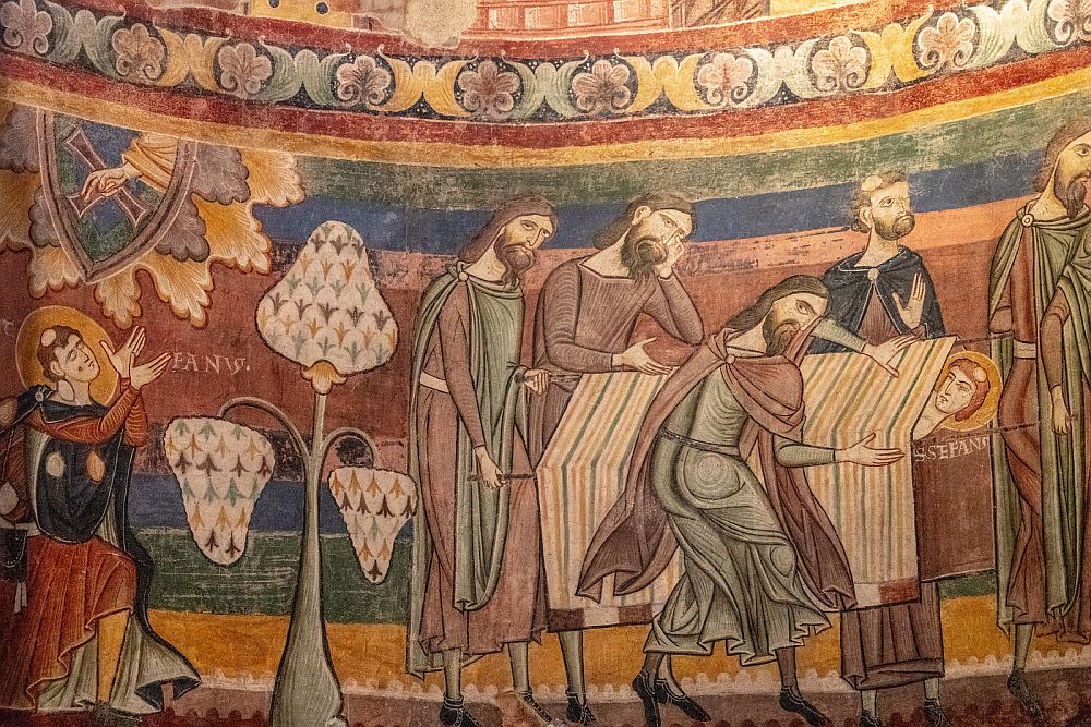 Medieval painting shows a man (Jesus?) with a halo lying down, covered with a cloth to his neck. Four men in robes look down at him.