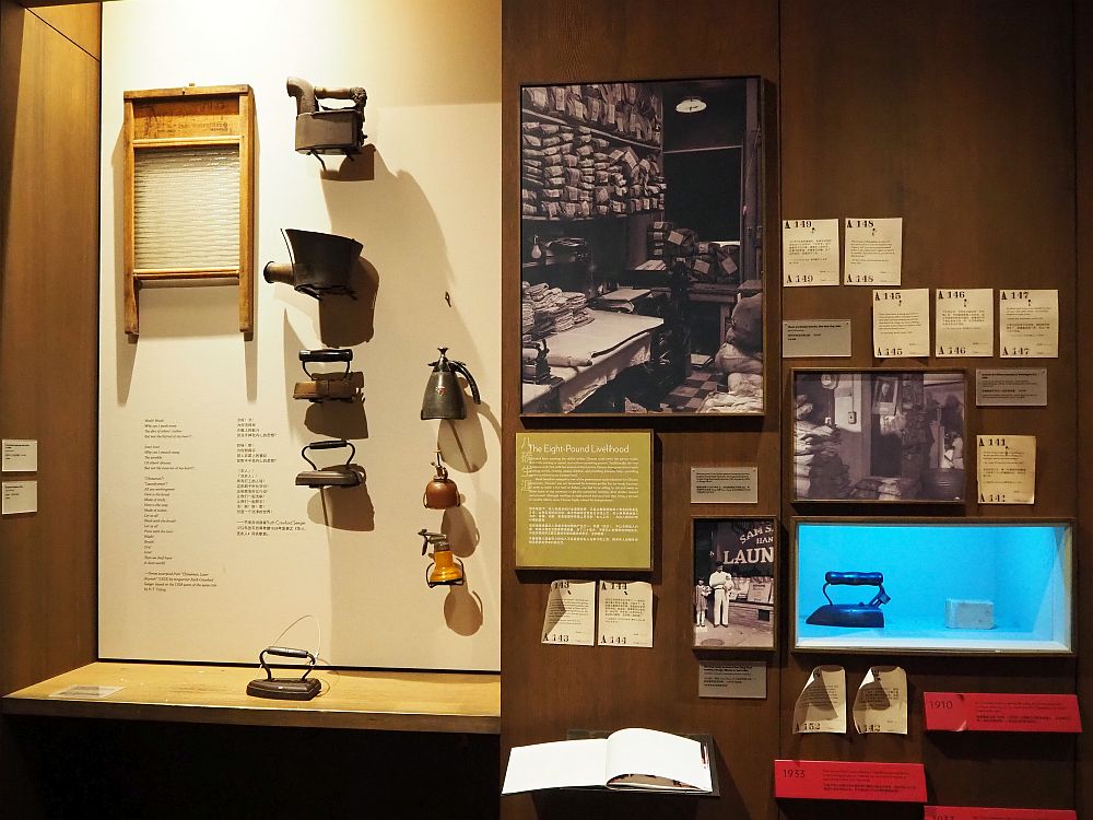 The display contains a number of items. On the left is a washboard and a number of irons and spray cans, along with one iron sitting on a shelf below them. On the right are some historicl photographs of Chinese laundries and various other documents from the period. A sign explains the Chinese laundry phenomenon.