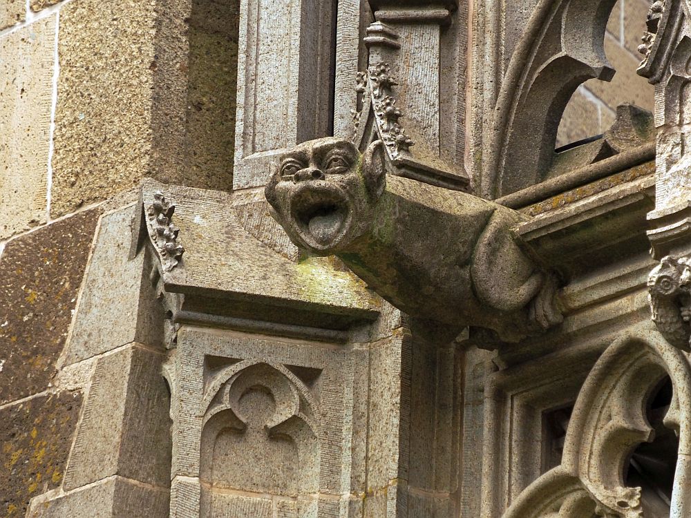 The gargoyle has a human face but an animals body and pointed ears. A devil? Its mouth is wide open.