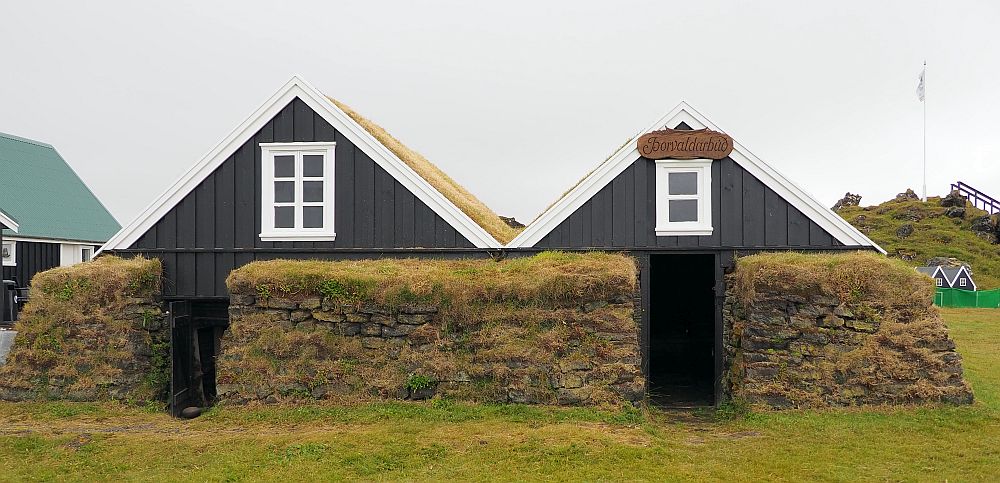 The fisherman's house has two fronts. Only the upper floor of each is fronted with wood. The rest is turf blocks covered in grass. The upper story of each front has a window, edged in white, but otherwise the wood is dark brown. 