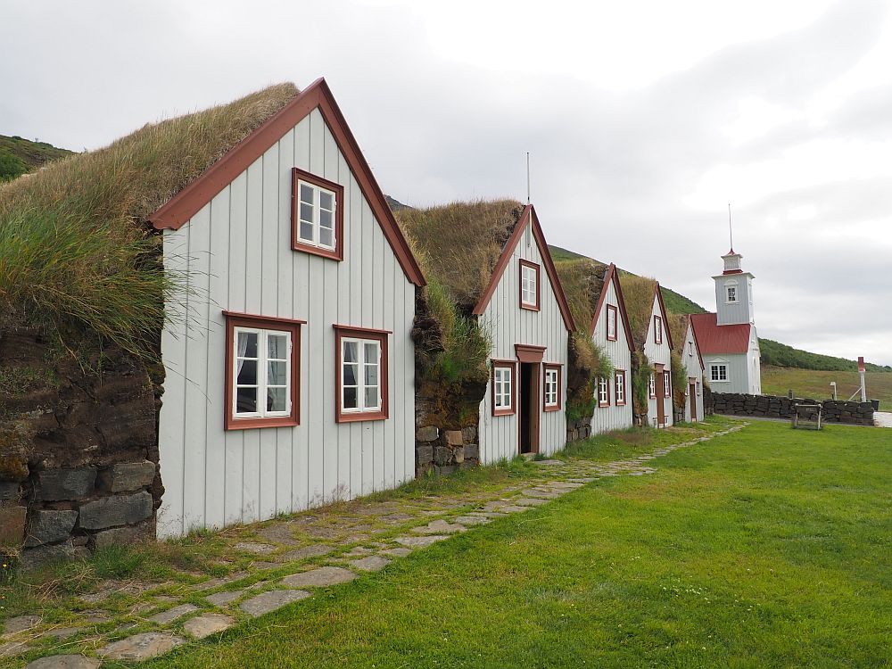 Seen from an angle to the side, the same five gable fronts as in the first picture in this article above. Just beyond them, the church is visible: white with a reddish roof and a small steeple.