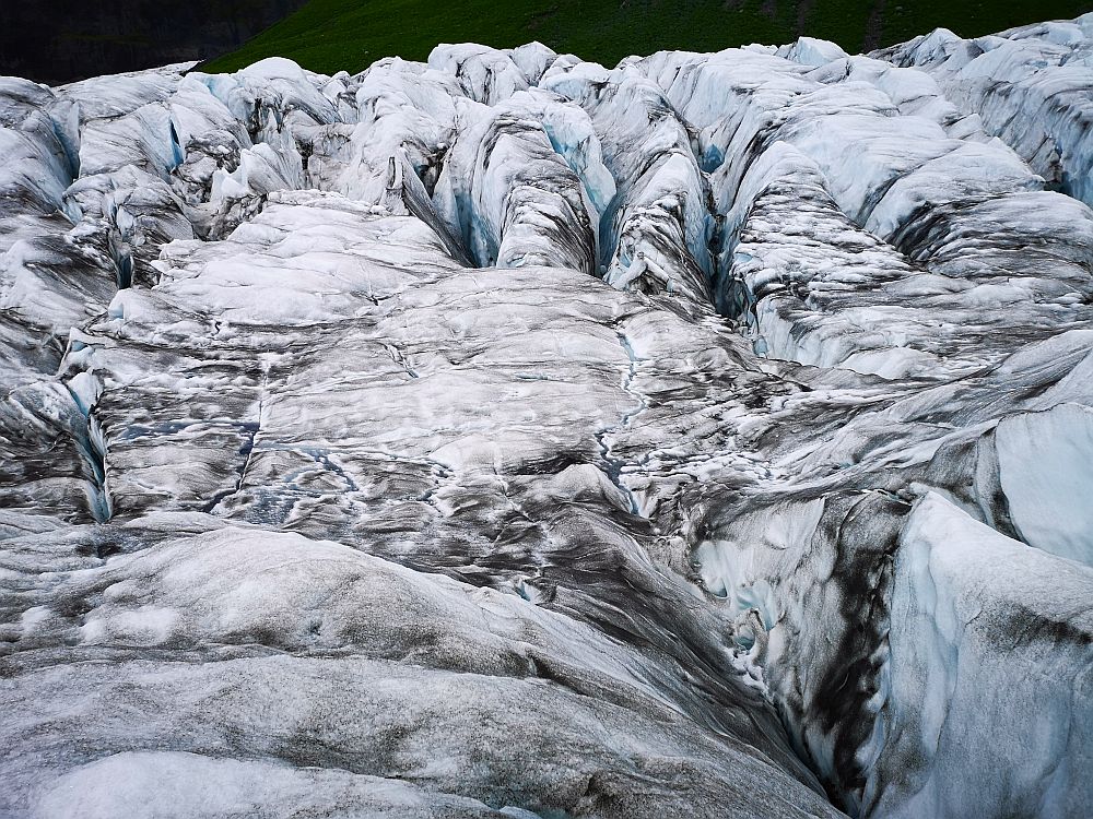 The ice is dirty white and looks almost wrinkled, with crevices carved into it. Unfortunately there is nothing in the picture to show the scale. 