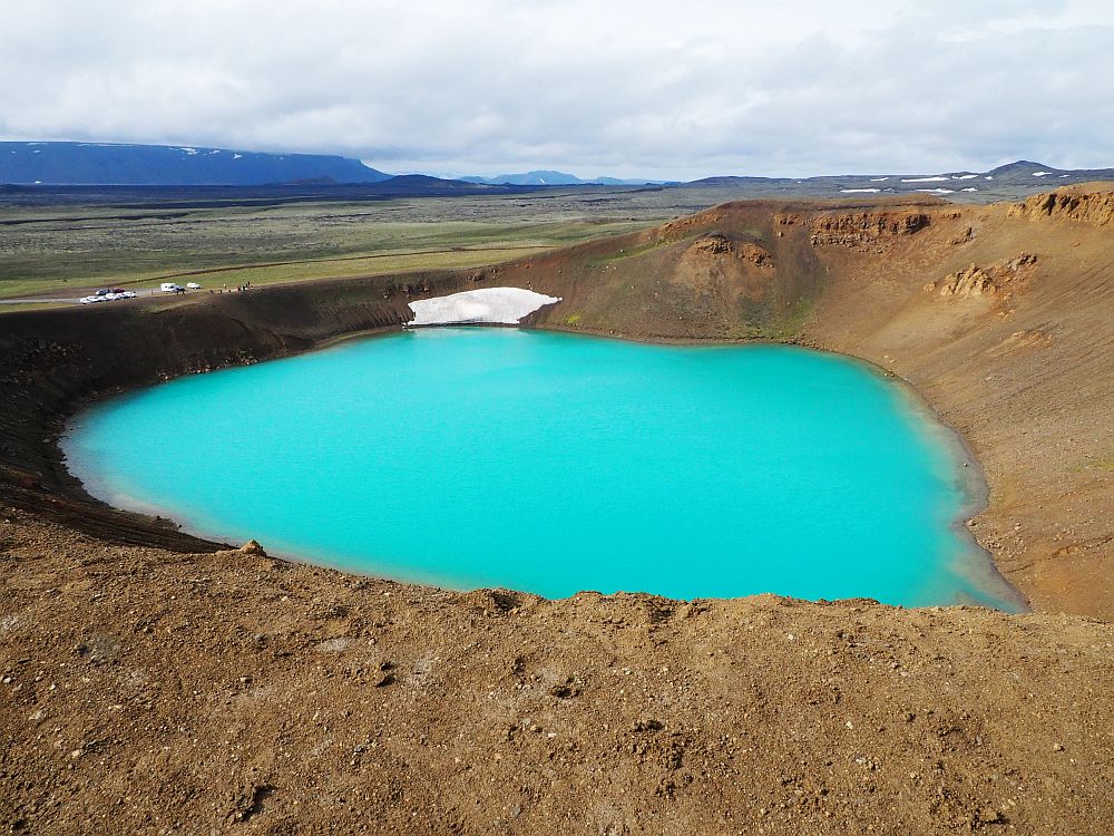 In this photo the crater doesn't look particularly deep, but the water inside it is a brilliant opaque aqua color, surrounded by brown dirt sides.