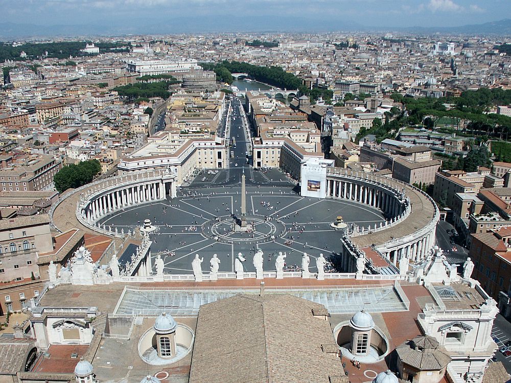 The square is actually round, with rounded colonnades along both sides, and a street extending straight opposite. A single column stands in the exact center of the square. Beyond and to the left and right is the city of Rome.