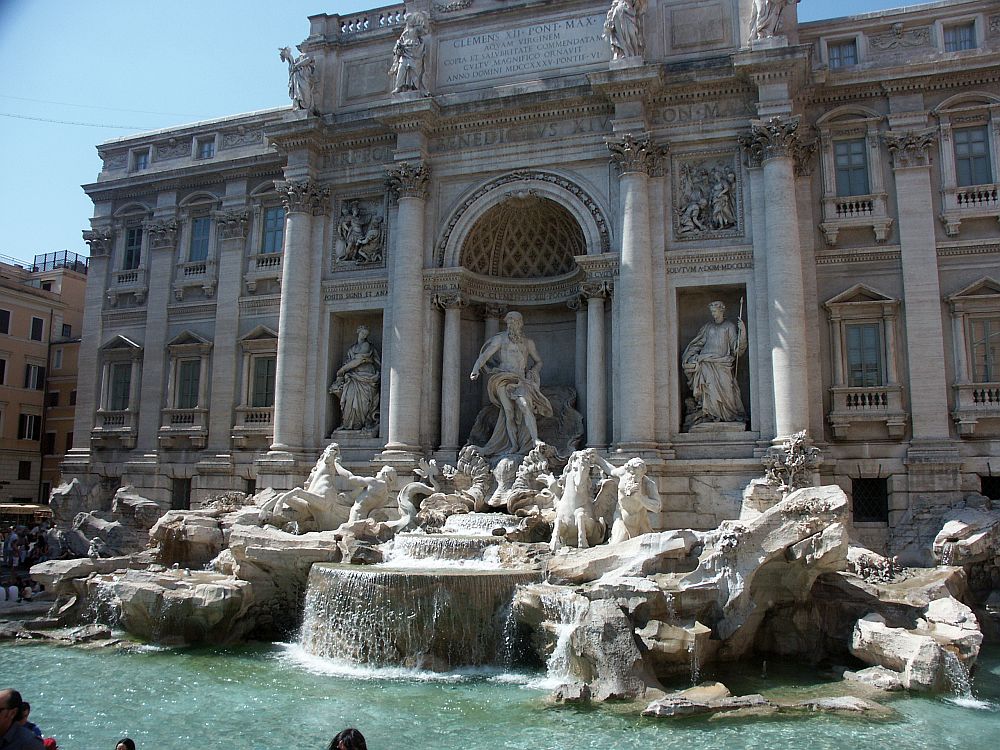 The Trevi Fountain is a sculptural fountain depicting, in white marble, Tritons and horces in motion, in front of a palazzo with corinthian columns. Very baroque. 