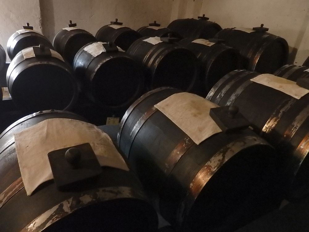 Barrels lie on their sides in rows. On top of each is a square white cloth.