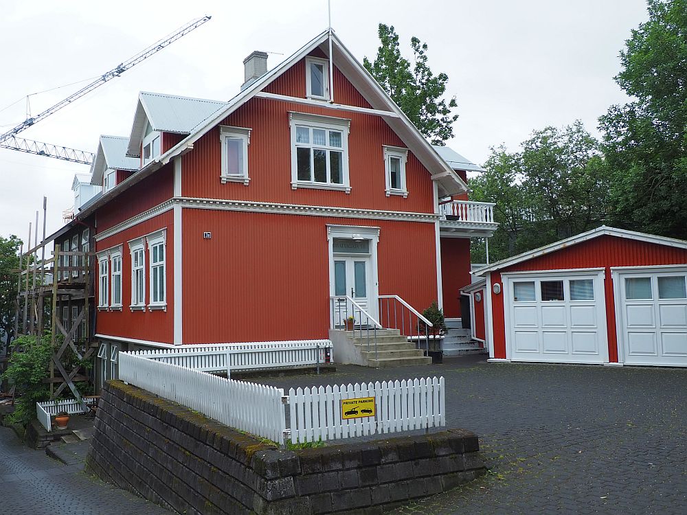 The how is two storeys with an additional small window under the peak of the roof. It is painted bright red with white trim.