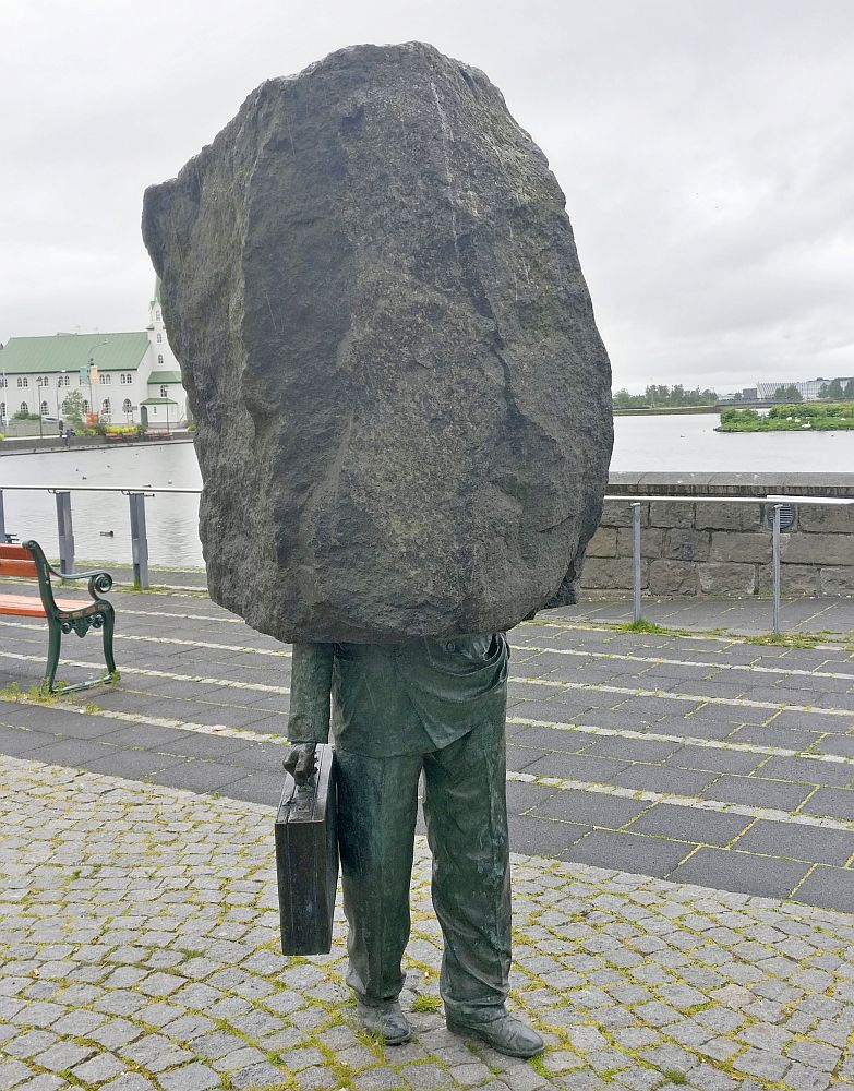 The bottom half of the statue is bronze and looks like the bottom half of a man wearing business clothes: neat trousers, work shoes, and in one hand, a briefcase. The top half is a huge stone: granite, I think, and just a rough, natural shape.