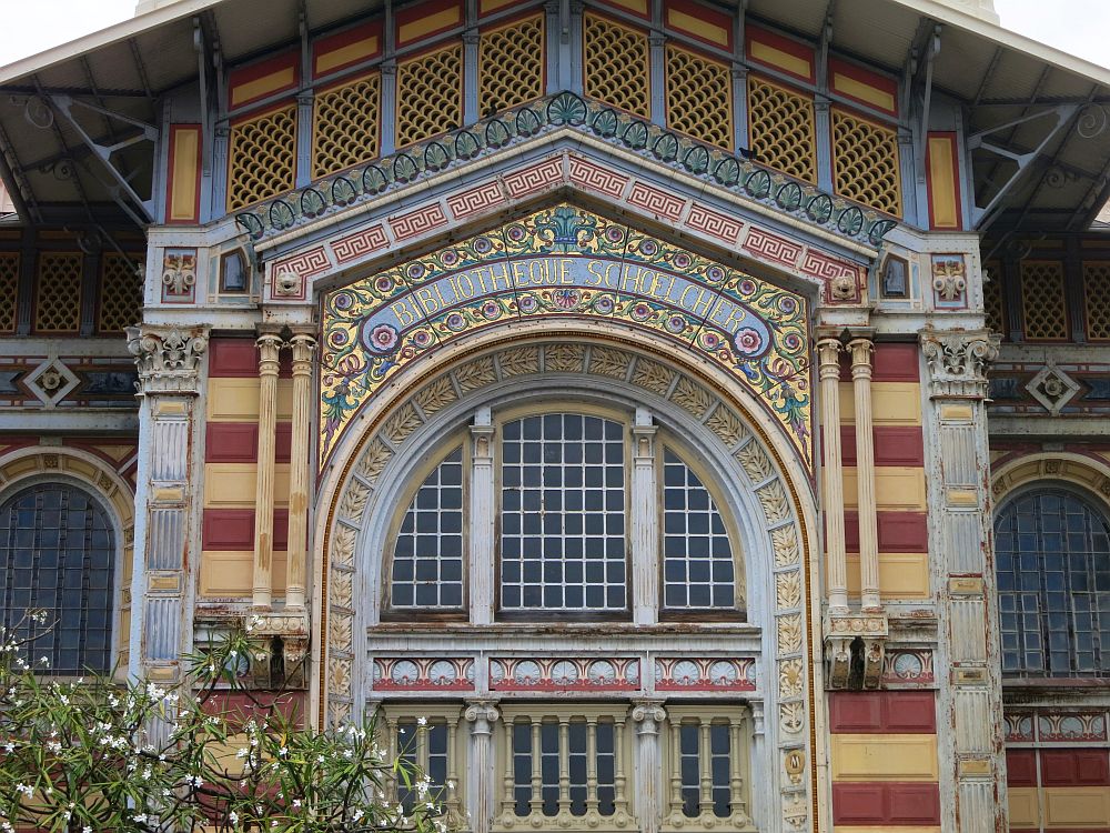 A close-up on the exterior of the library shows very detailed and colorfful art nouveau tiling covering every inch of the exterior. Shown is one arched window and the decoration above and beside it.