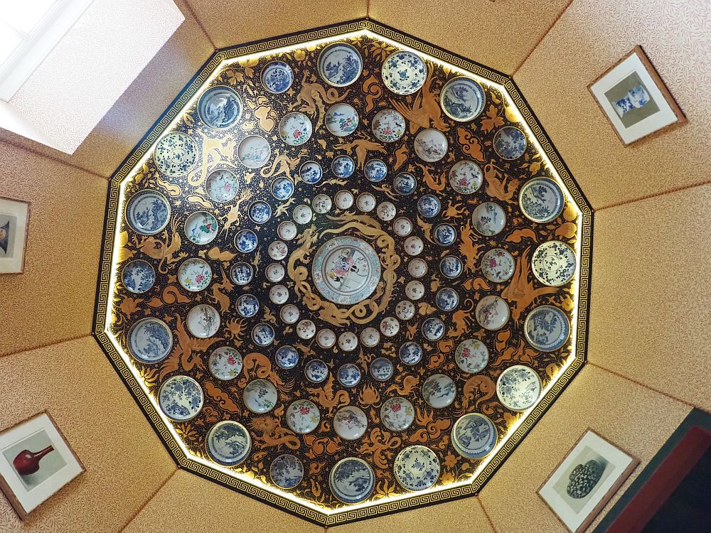 Looking straight up, a 10-sided room. The ceiling has 4 concentric circles of porcelein plates, smaller in the inner rings, getting larger to the outer ring, with a quite large one in the center. It looks like every plate is different, but the dominant colors are blue and white. Between the plates seems to be painted, mostly in a gold and black or dark blue pattern.