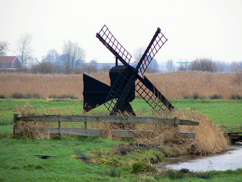 A small wooden windmill in a field.