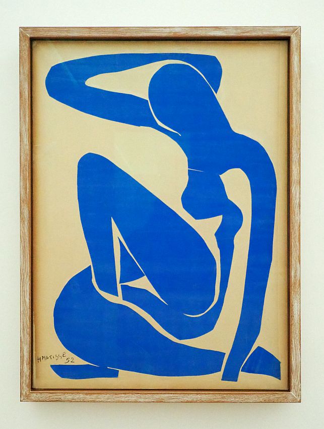 An abstract series of blue cutouts make the general shape of a woman. She sits with one knee up and the other leg curled around her on the floor. One arm touches the floor, while the other is bent up and almost touches the back of her head.