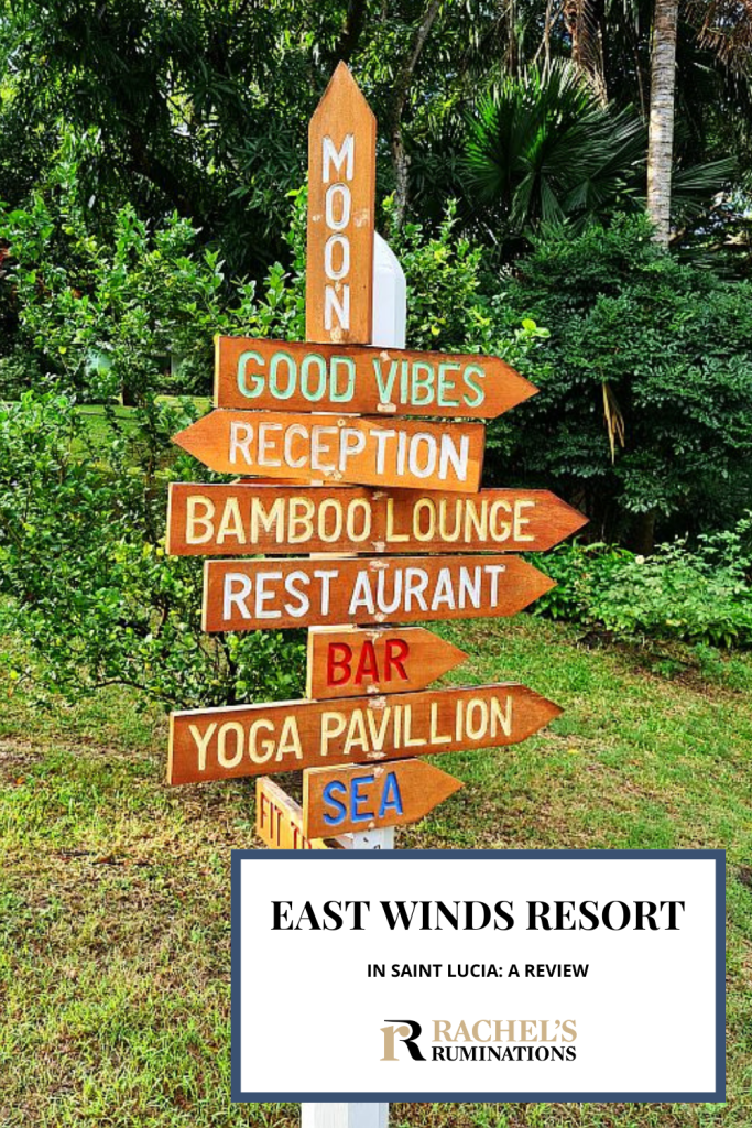 Text: East Winds Resort in Saint Lucia: A review (and the Rachel's Ruminations logo). Image: a vertical pole with a number of wooden arrows attached to it. From top to bottom: Moon (points up), good vibes, reception, bamboo lounge, restaurant, bar, yoga pavilion, sea.