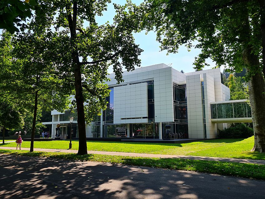 A contemporary buiding, with large flat white walls that seem to float in simple rectangles and squares, and some glass walls visible between the white walls. 