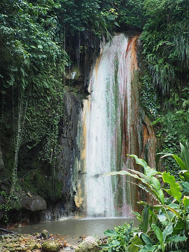 Diamond Falls is high and somewhat wider than Toraille Falls, and also falls down a greenery-covered cliff. The stone at the sides of the waterfall is stained in shades of reds and browns.