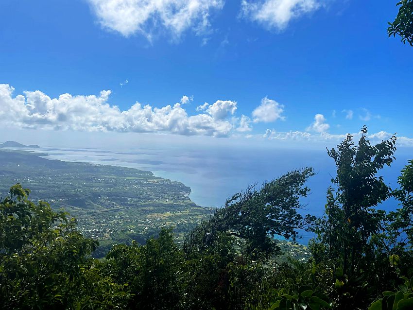 A very big view, with a rather flat landscape of Saint Lucia, very green but with scattered houses, and the sea next to that. A row of clouds in the distance shows how high up this picture was taken.