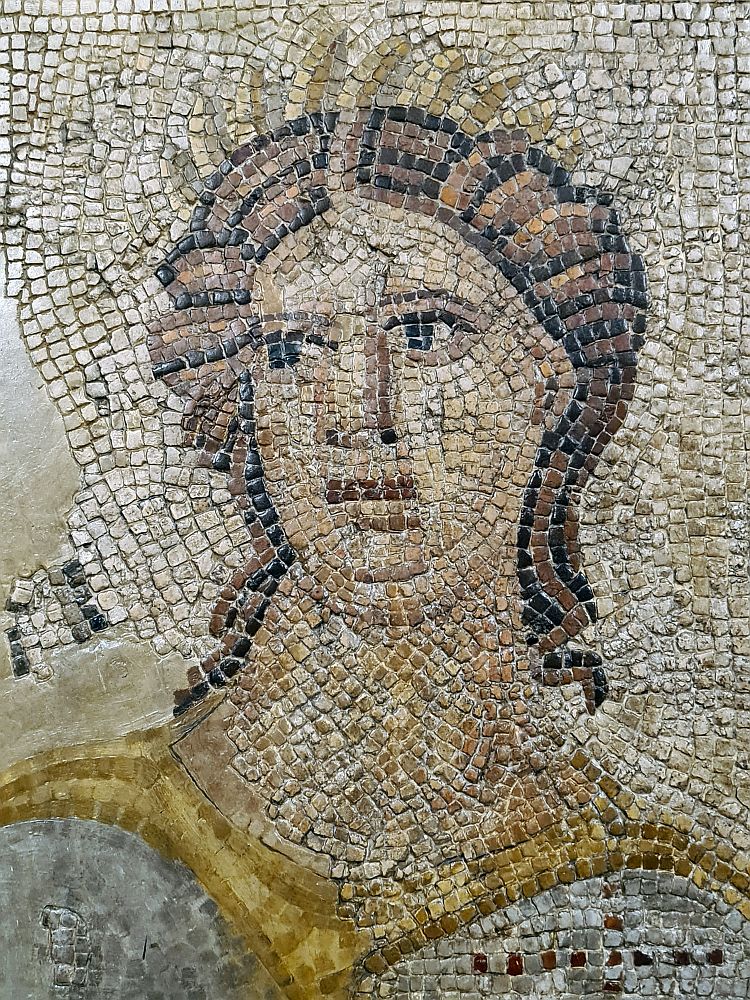 A close-up of one of the squares depicting a muse. The mosaic tiles are squared and only a few are missing to the side of the face.