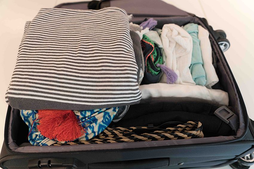 A wheeled bag open to show its contents. The right half (the bottom of the suitcase) has the clothing folded so each item is visible from its side. On the left, more traditional packing, with the clothing in a pile.