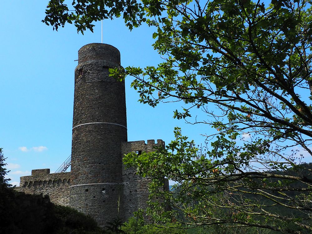 A tall cylindrical tower and plain stone walls, partly crenellated at the top.