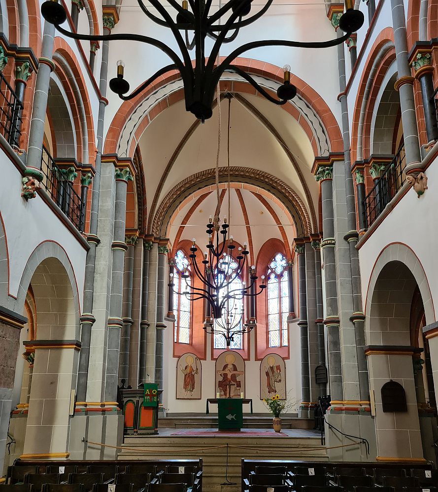 Rounded arches, supported by pillars, pews at the bottom of the photo, a very simple altar at the far end of the church.