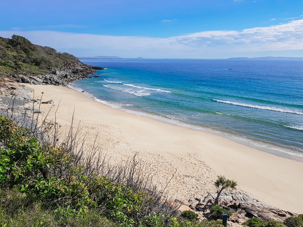 View of a small white-sand beach on the Queensland coast, completely empty, and the blue sea.