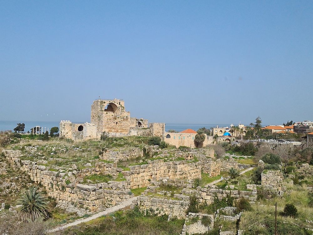 A small hill with ruins of a fortress on top and traces of various walls around it on the hill.