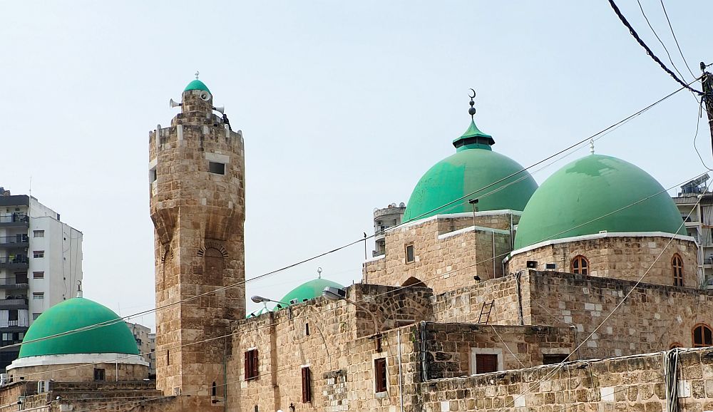 A stone-built mosque with 4 green domes visible in this photo, and a stone minaret. 
Lebanon travel tips