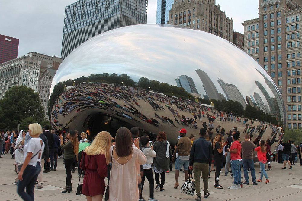 The sculpture called "The Bean" reflects the people around it and the skyscrapers behind them. 