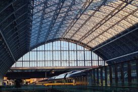 A view of the inside of St. Pancras station in London, with its huge arched glass ceiling over the train tracks.