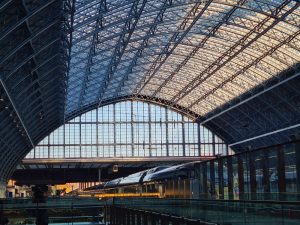 A view of the inside of St. Pancras station in London, with its huge arched glass ceiling over the train tracks.