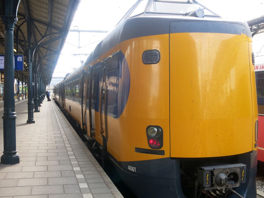 A big yellow and blue Dutch train sits at the station platform.
Sustainable travel tips.