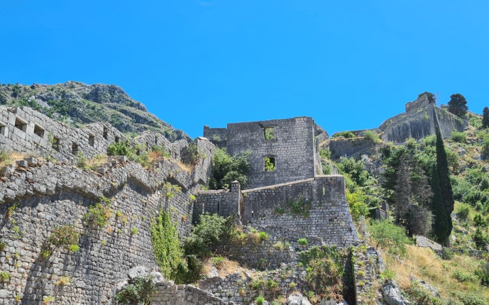 Stone walls on the left leading up to Kotor Fortress, far up on the hill ahead.