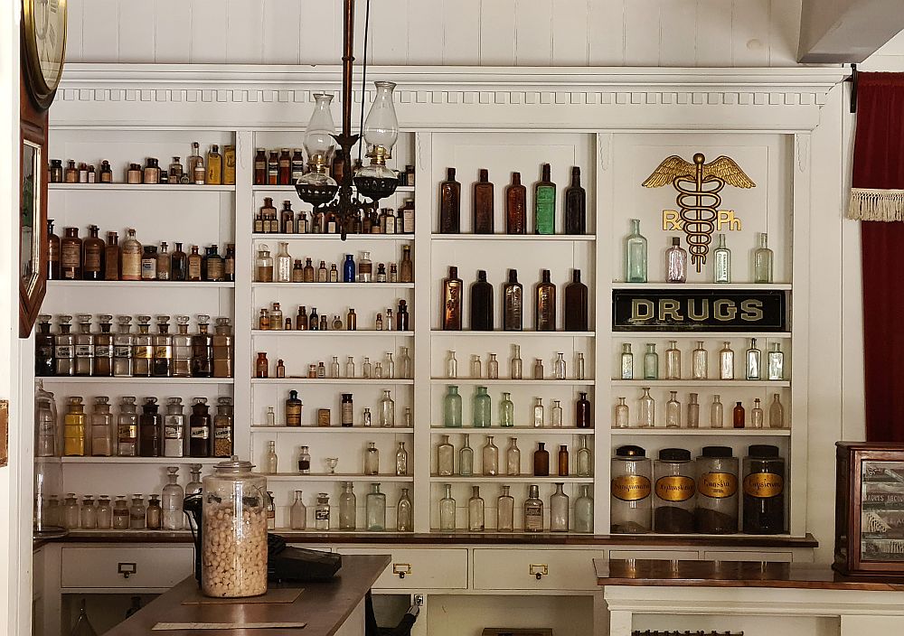 White-painted shelves cover a wall - neat rows of bottles of various sizes on the shelves. 