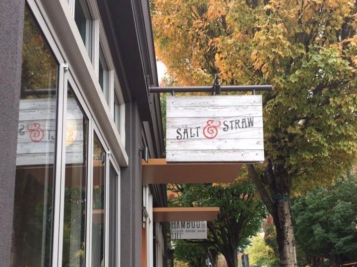 A storefront seen from the side, so just the sign sticking out from the building is visible, and a tree behind it. The sign reads "Salt & Straw".