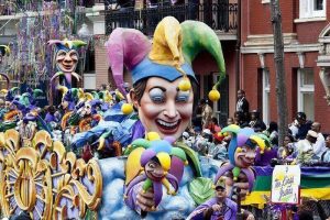 A float moving through a crowd full of large figures of court jesters with the typical jester hats.