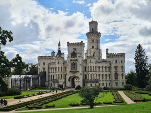 Exterior view of Hluboká Castle, complete with crenellations along the roof and a tall tower.