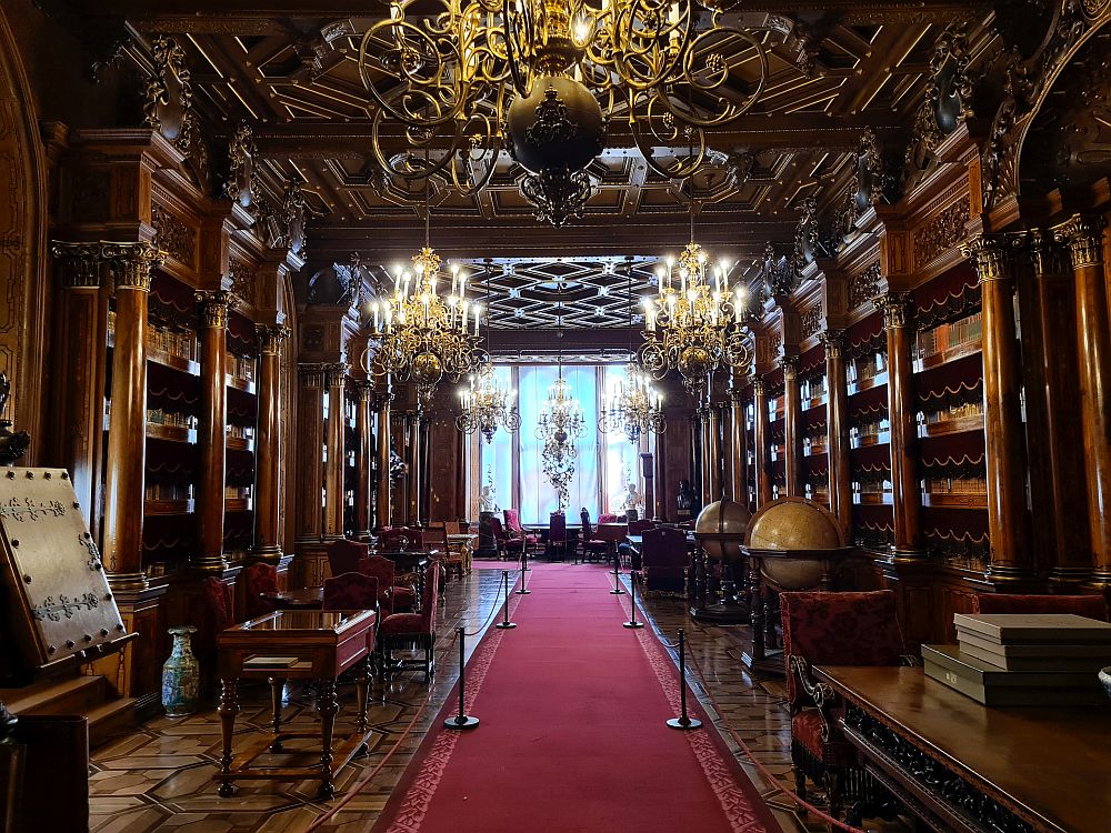 A long hall, with ornately-carved shelves filled with books on both sides. 