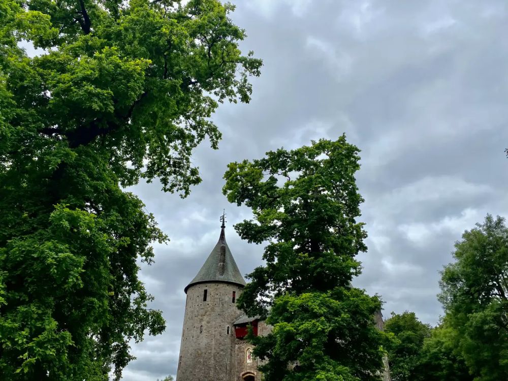 Top of the castle, with a cylindrical stone tower topped with a pointed grey roof.