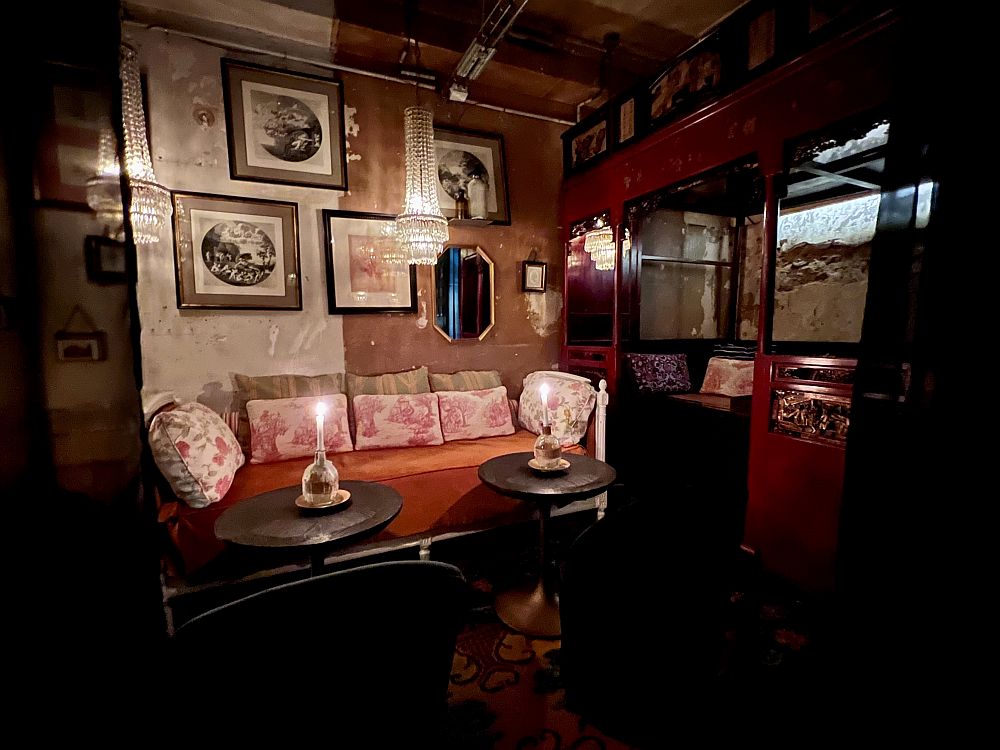 Inside of a pub: couches, pillows, a long-unpainted wall.