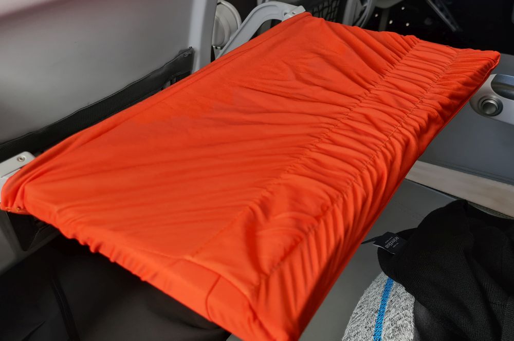 Airplane tray table covered in orange material.