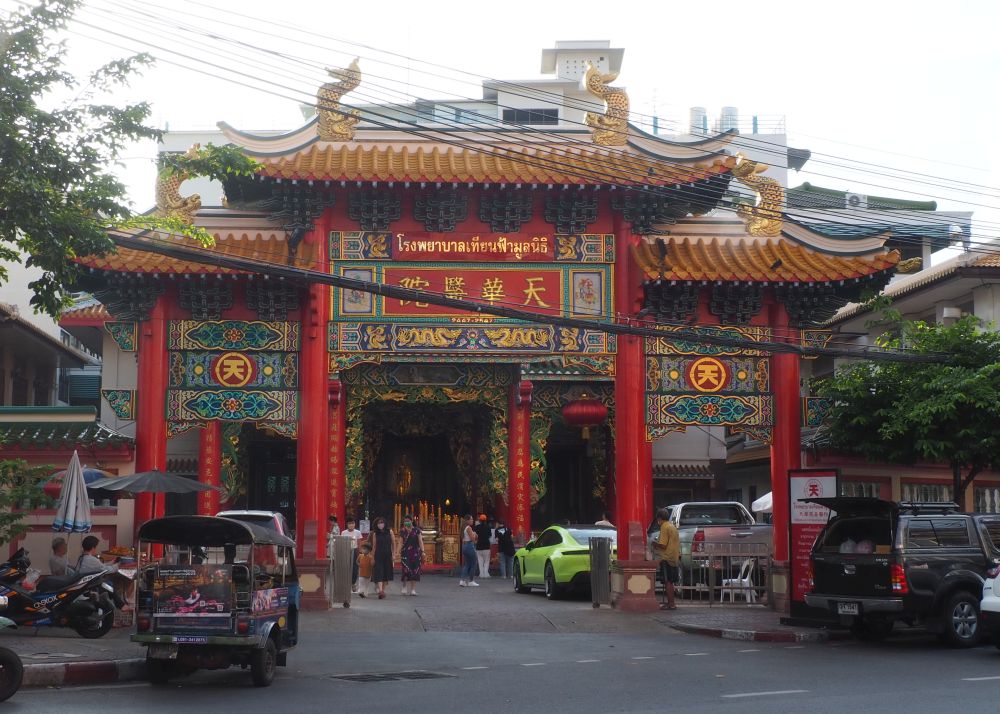 A large, colorful entrance gate obscures the temple itself. It's red and has Chinese lettering on it.