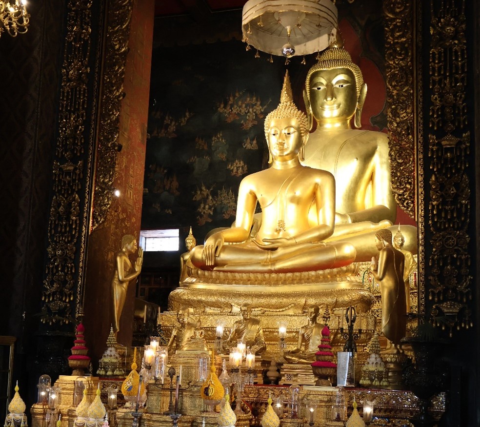 Two golden sitting Buddhas, one right in front of the other, larger one.