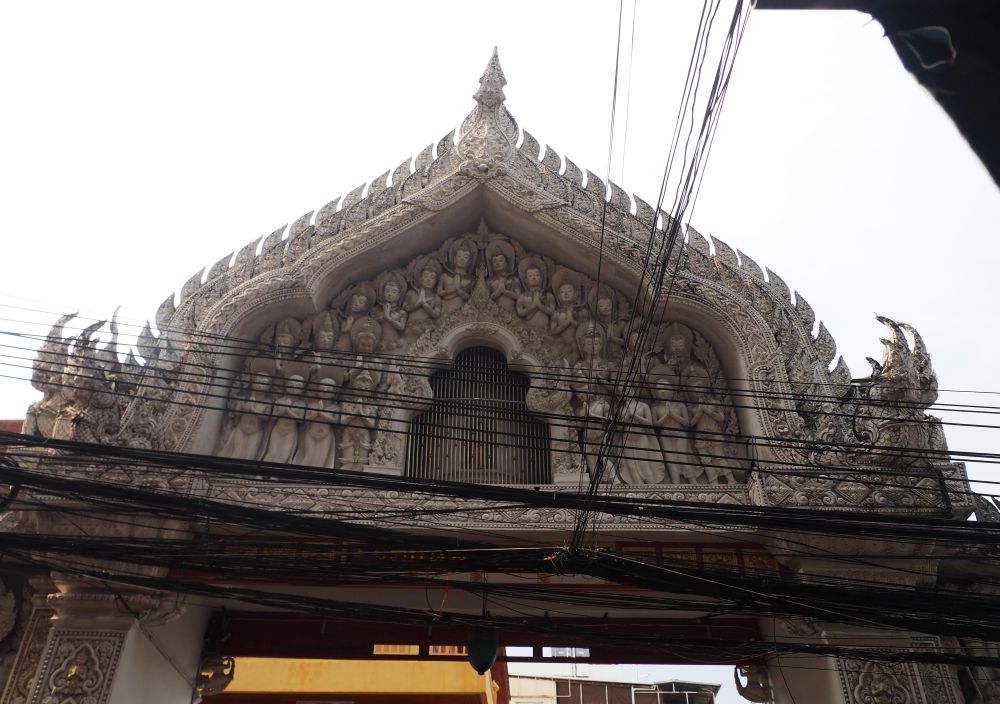 The gateway is in the shape of a gothic arch with, inside it, rows and rows of praying Buddhas in a bas-relief.