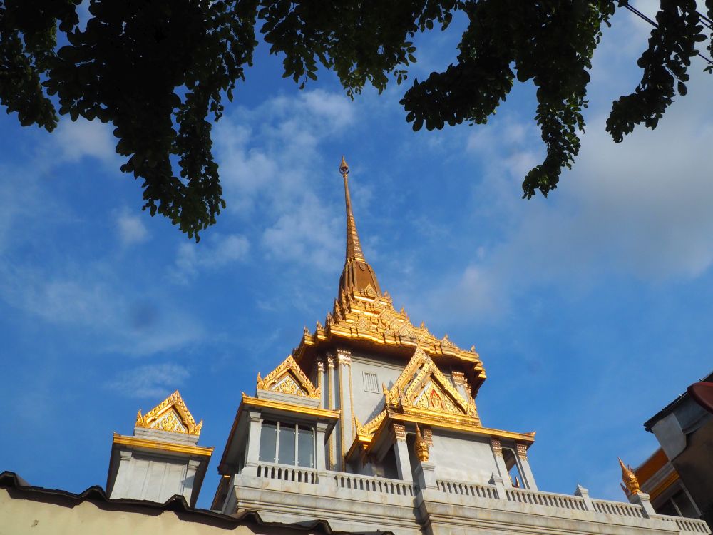 Back view up at Wat Traimit, gold decorations over the windows, and a gold stupa on the roof.