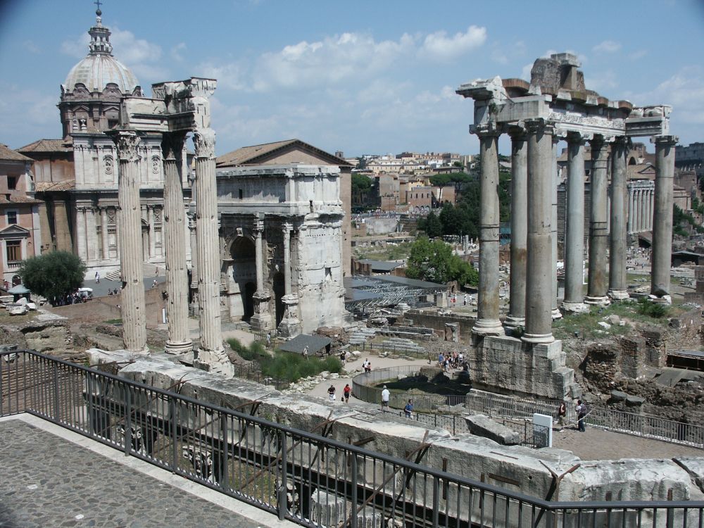 A view of the Roman Forum with several sets of tall columns and a large archway.