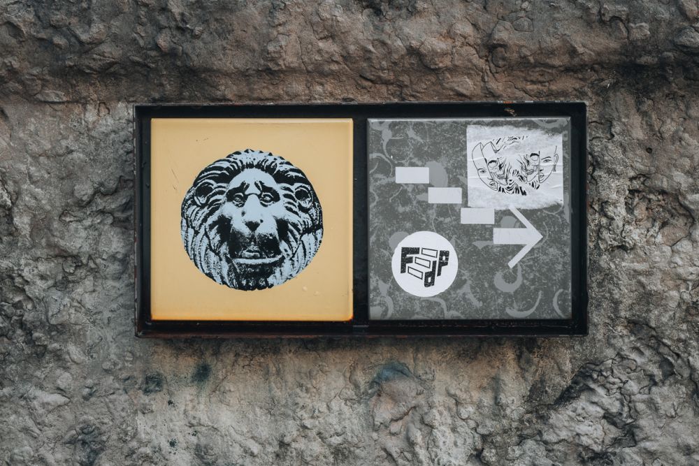 The sign shows a photo of a lion carving on the left and an arrow shaped like a stairway on the right.