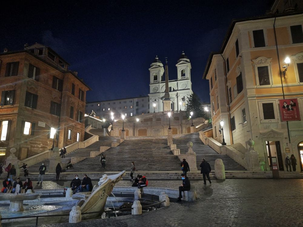 Nighttime view up the Spanish steps, lit by lights along the sides, with the church at the top also lit up.